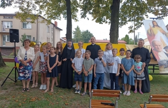 Dzieci po przedstawieniu pozuja z kobieta oraz dwoma ksiezmi