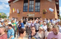 Kilkudziesięciu wiernych stojących pod kościołem 