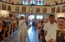 Wierni w kościele. Przez środek przechodzący ksiądz z kropidłem 